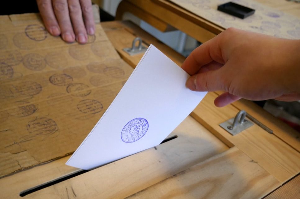 Une personne introduit son vote dans une urne.