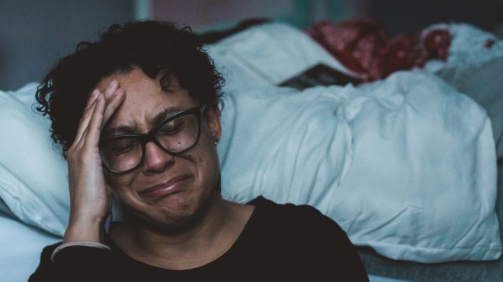Une femme pleurant dans une chambre (Image : Unplash).