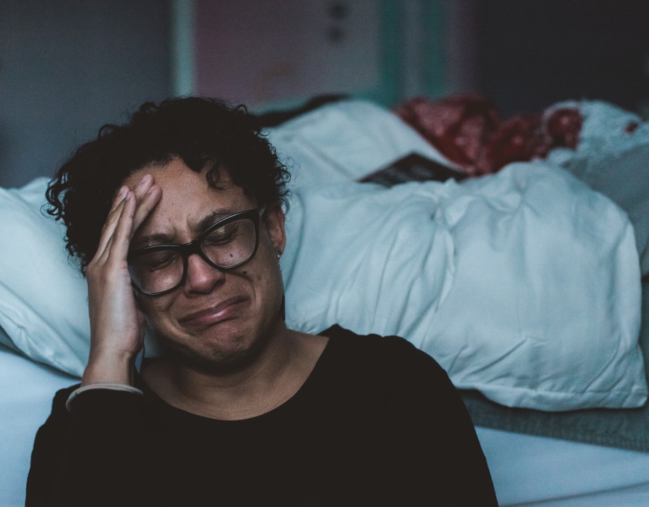 Une femme pleurant dans une chambre (Image : Unplash).