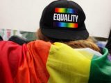Une personne vue de dos avec un drapeau LGBT.