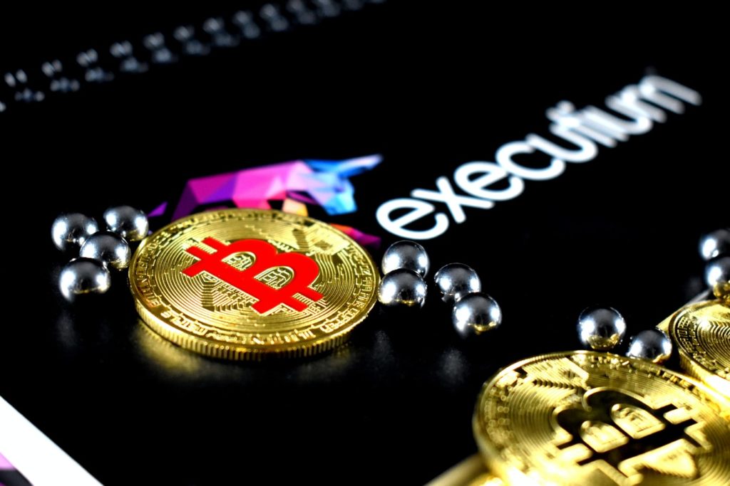 Une pièce de Bitcoin à côté d'un logo d'executium.